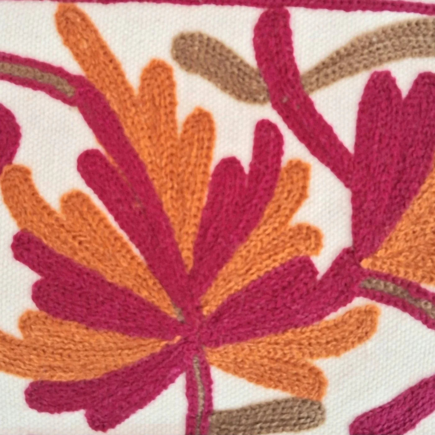 Close-up of colorful embroidered floral pattern on fabric with orange, pink, and brown threads