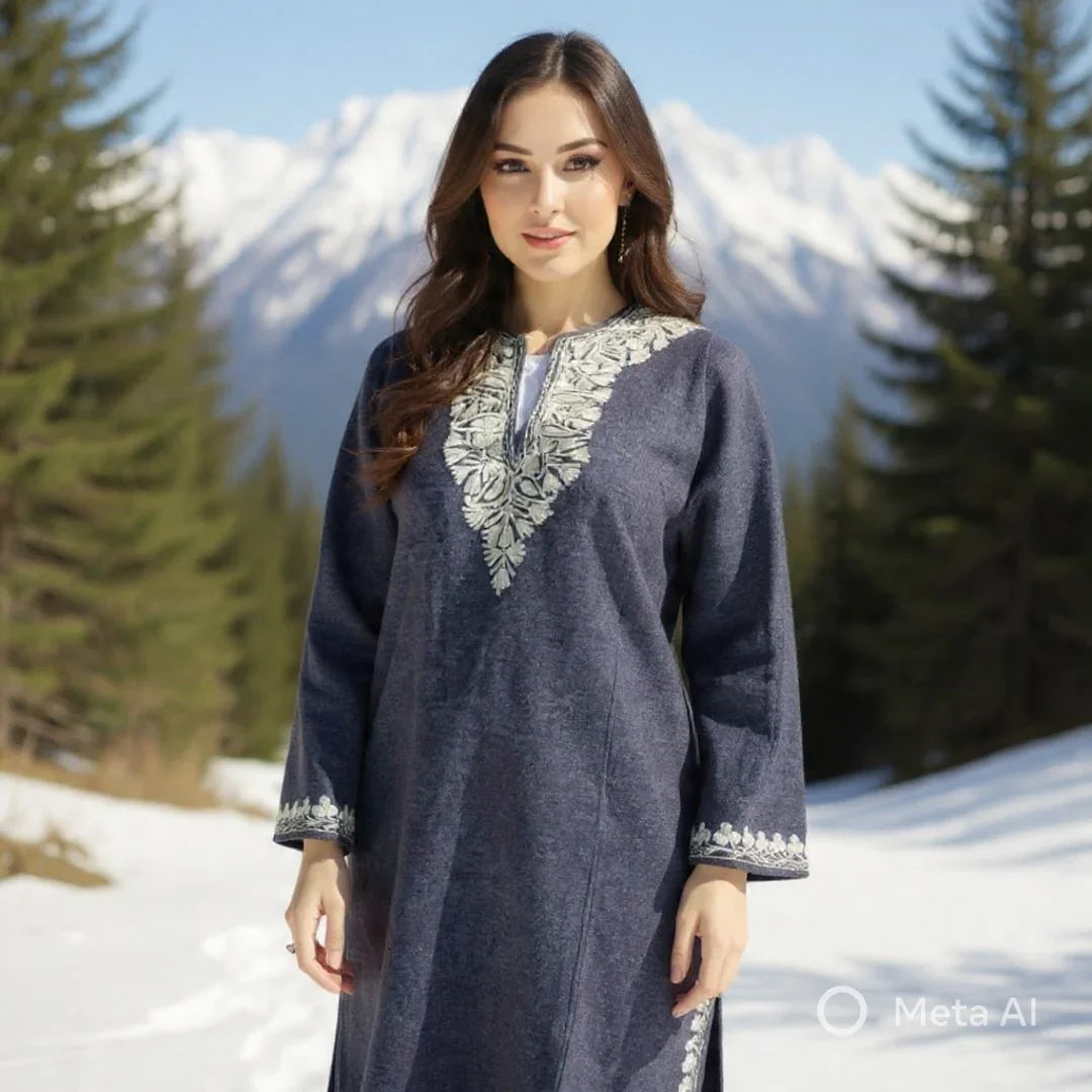 Woman wearing a navy blue embroidered Pashmina shawl dress standing outdoors with snow, pine trees, and mountains