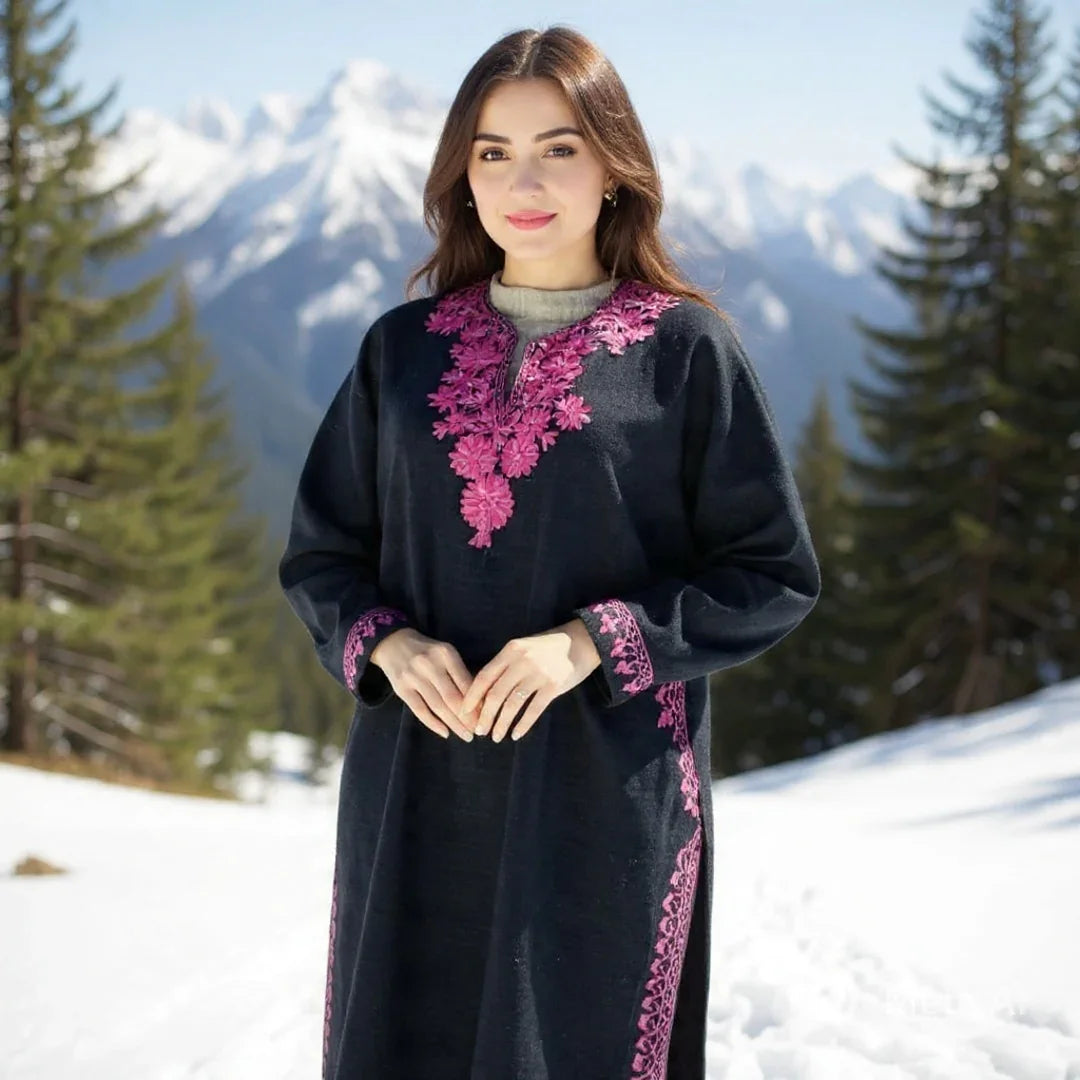 Woman wearing black woolen Kashmiri dress with pink embroidery in snowy mountainous landscape