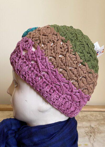 Multicolor handwoven woolen cap with green, brown, and purple sections displayed on mannequin head