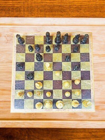 Stone marble chess set with black and white pieces on checkered board by Zanskar Arts