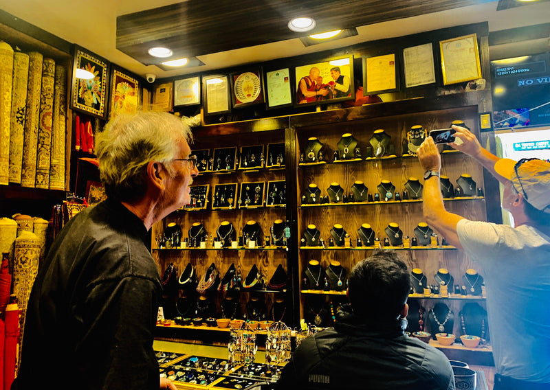 Customers browsing traditional jewelry and accessories in Zanskar Arts store with framed certificates and rugs displayed