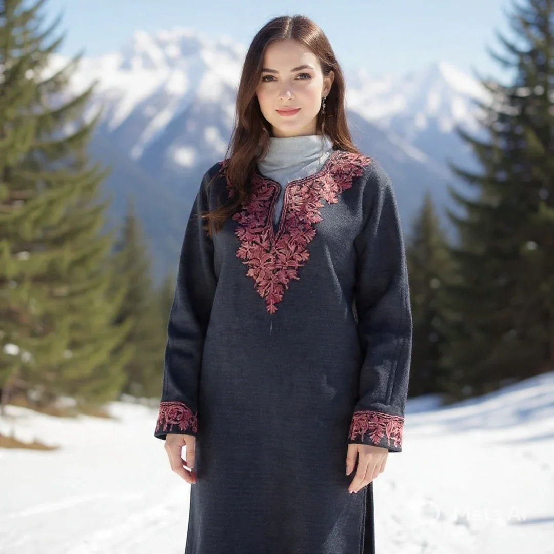 Woman wearing navy blue embroidered wool dress with pink floral patterns in snowy mountainous forest