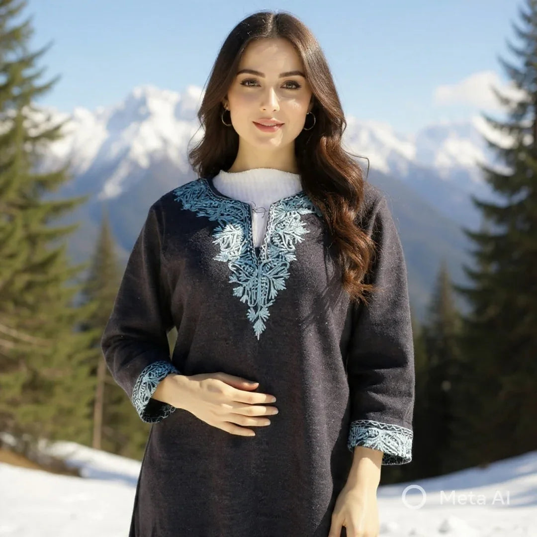 Woman wearing dark woolen Kurti with blue embroidery in snowy mountain landscape, evergreen trees