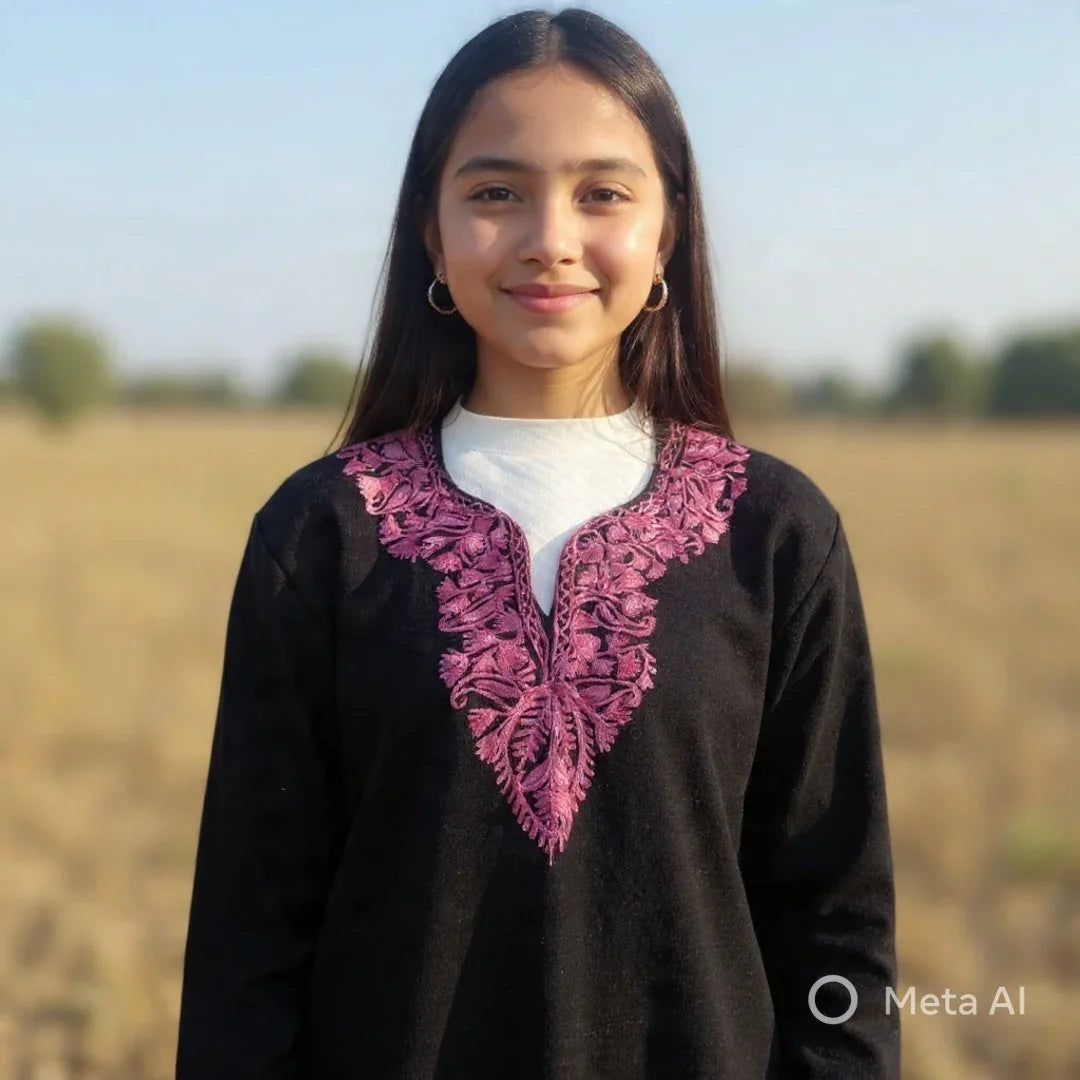 Young woman outdoors wearing black pashmina sweater with pink floral embroidery, natural background